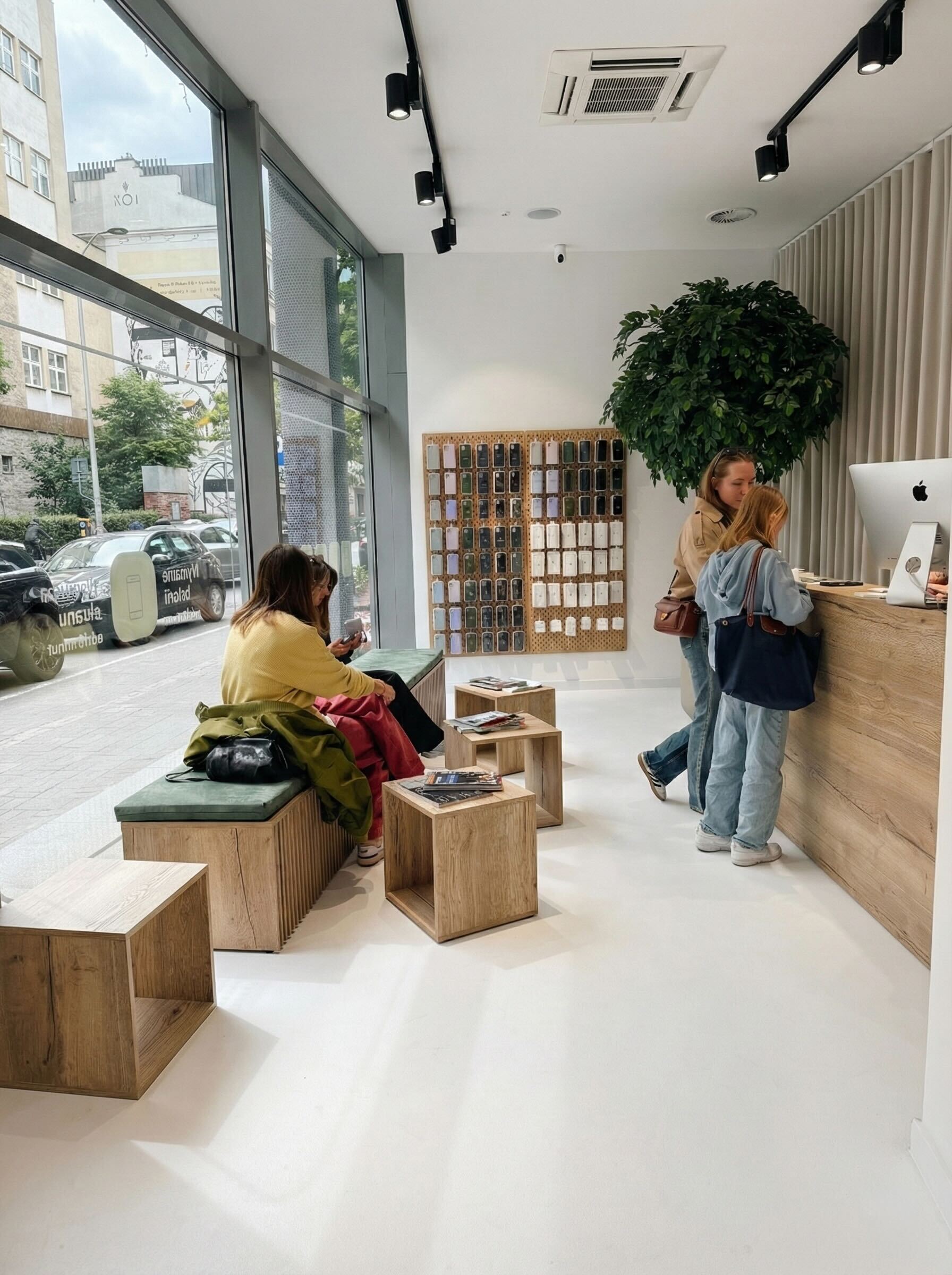 Klientki podczas wizyty w serwisie Apple Flix — obsługa przy ladzie napraw iPhone